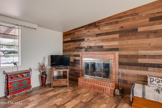 living room with wood walls, a fireplace, vaulted ceiling, and wood finished floors