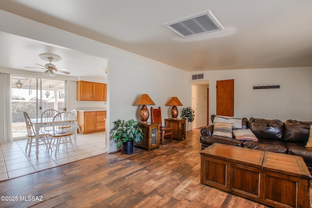 living area featuring visible vents, ceiling fan, and wood finished floors