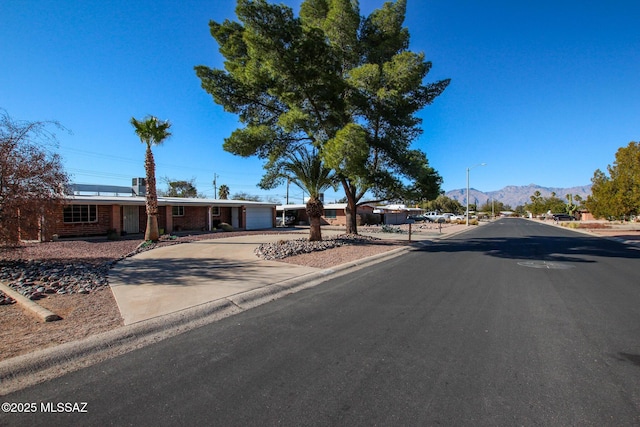 view of street featuring sidewalks, street lighting, a mountain view, and curbs