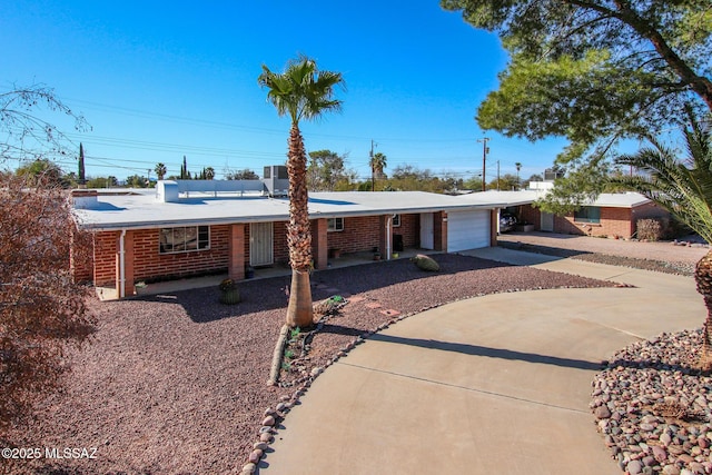 ranch-style house with an attached garage, central air condition unit, concrete driveway, and brick siding