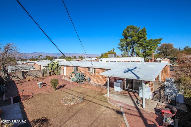 rear view of house featuring brick siding, a patio area, fence, and a mountain view