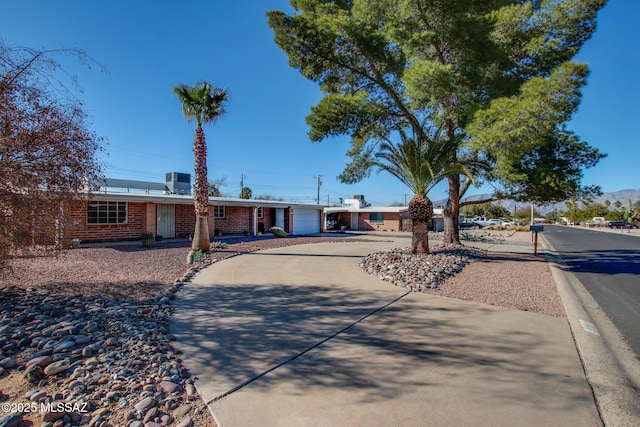 ranch-style house featuring an attached garage, concrete driveway, and brick siding