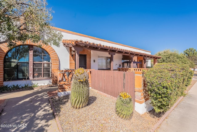 view of front of home featuring a fenced front yard, a tiled roof, and stucco siding