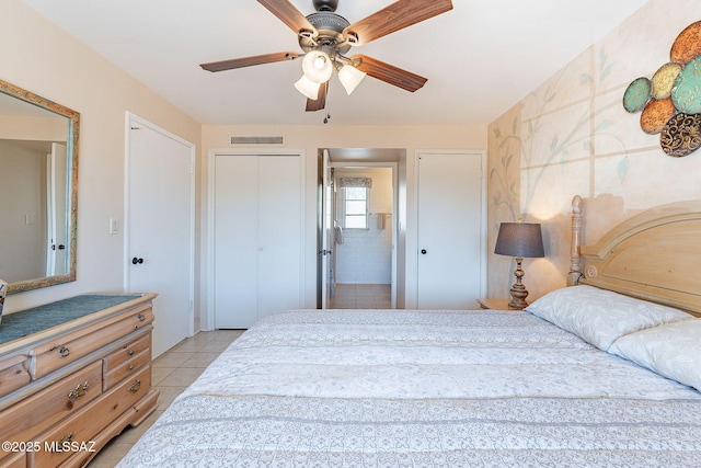 bedroom with a ceiling fan, visible vents, connected bathroom, and light tile patterned floors