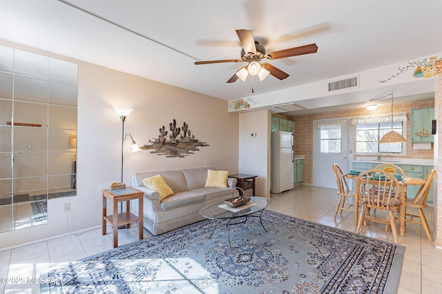 living room featuring light tile patterned floors, visible vents, and a ceiling fan