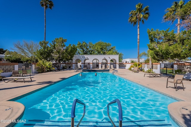 pool with a patio area and fence