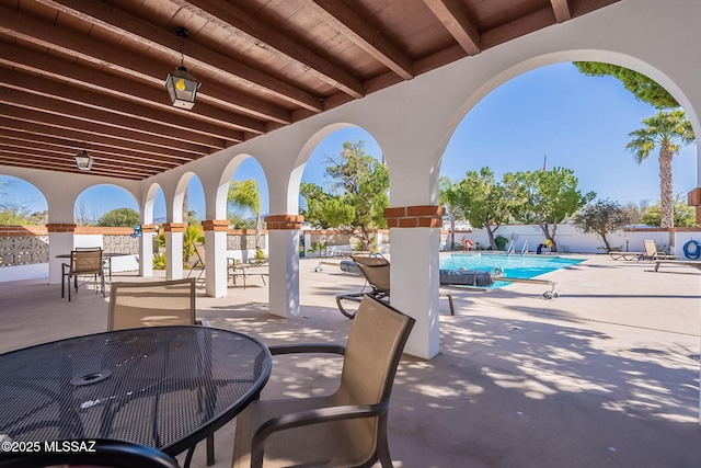 view of patio featuring a community pool, fence, and outdoor dining space