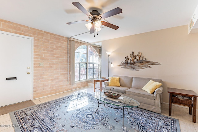 living area featuring brick wall, tile patterned flooring, and a ceiling fan