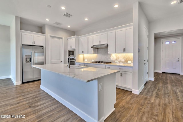 30776 S Sand Hurst Ln, Oracle, AZ 85623 - kitchen with stainless steel appliances, a sink, under cabinet range hood, white cabinetry, and wood finished floors