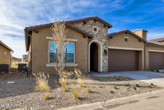 mediterranean / spanish home with driveway, stone siding, a garage, and stucco siding