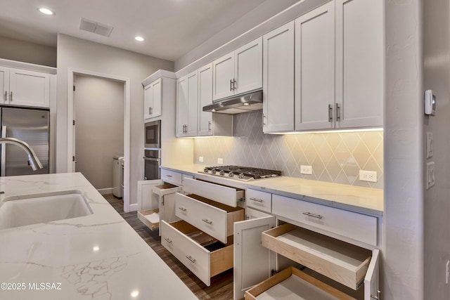 30776 S Sand Hurst Ln, Oracle, AZ 85623 - kitchen featuring under cabinet range hood, appliances with stainless steel finishes, a sink, white cabinets, and backsplash