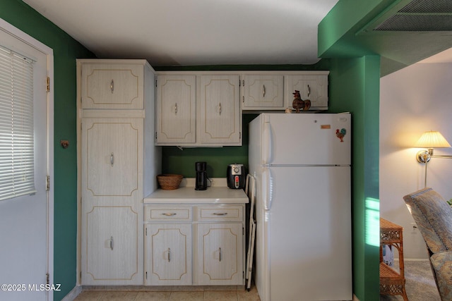 kitchen with freestanding refrigerator, light countertops, baseboards, and white cabinetry