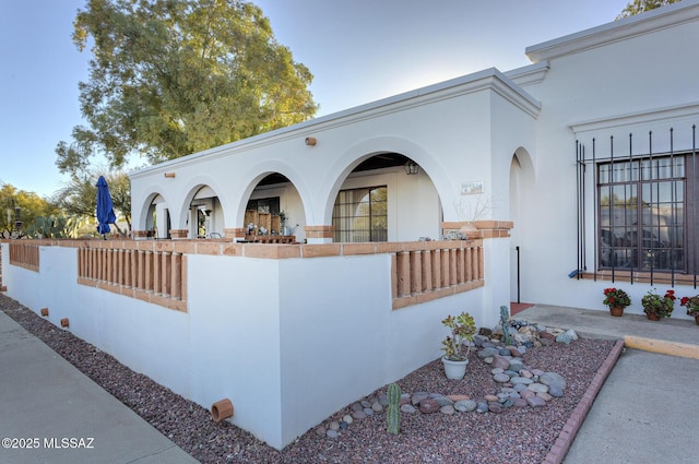 view of side of property with fence and stucco siding