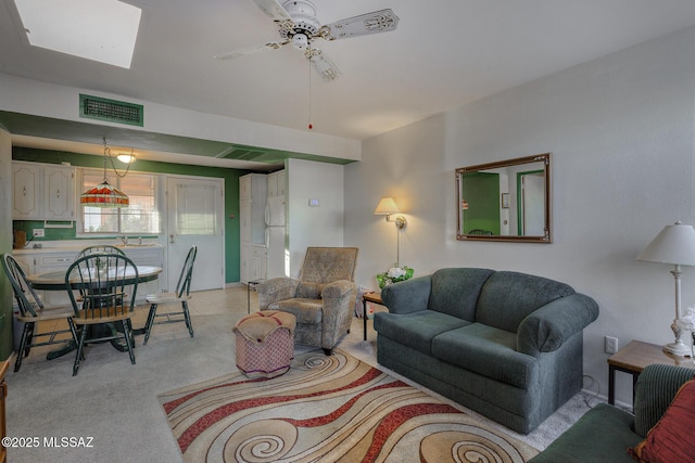 living area with visible vents, ceiling fan, and light carpet