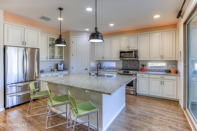 kitchen featuring visible vents, stainless steel appliances, light wood-style floors, white cabinetry, and a sink