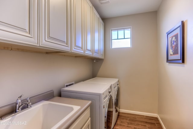 laundry area with a sink, washing machine and dryer, cabinet space, light wood-style floors, and baseboards