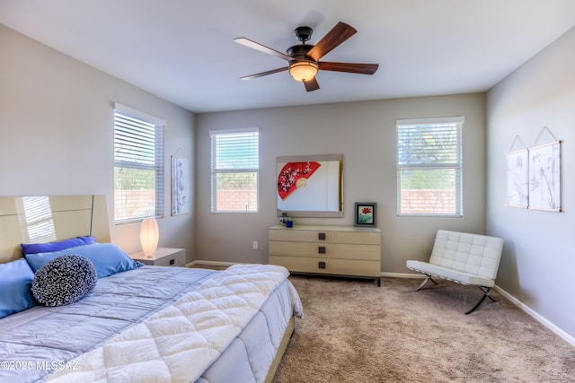 carpeted bedroom with multiple windows, a ceiling fan, and baseboards