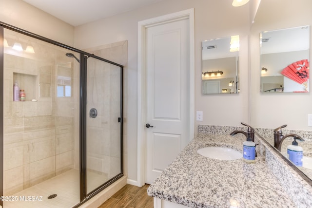 bathroom with visible vents, a stall shower, vanity, and wood finished floors