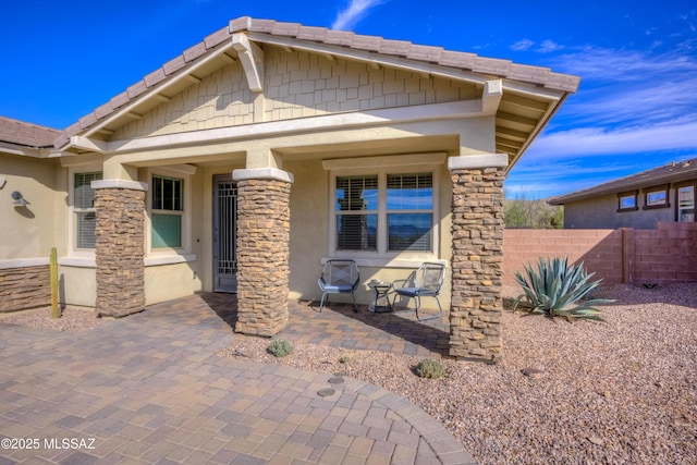 exterior space featuring fence, stone siding, and stucco siding