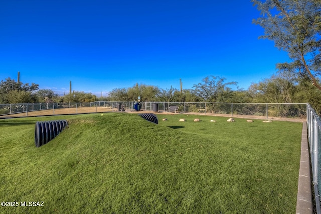 view of property's community featuring a lawn and fence