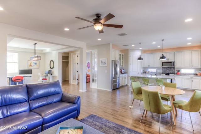 living room featuring visible vents, baseboards, recessed lighting, wood finished floors, and a ceiling fan