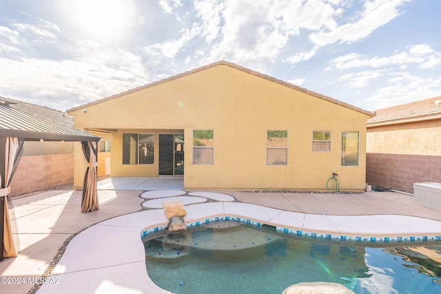 rear view of house with a patio, stucco siding, a gazebo, a fenced backyard, and an outdoor pool