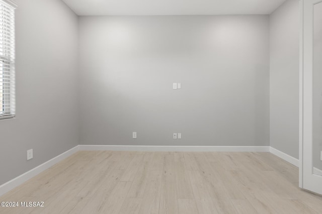 unfurnished room with light wood finished floors, plenty of natural light, and baseboards