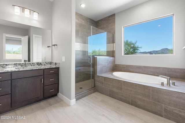 full bathroom featuring a stall shower, baseboards, a bath, and vanity