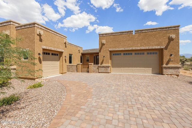 view of front facade with decorative driveway, an attached garage, and stucco siding