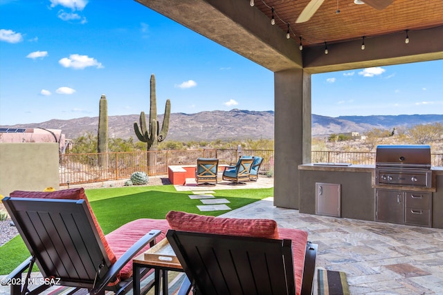 view of patio / terrace with exterior kitchen, a fenced backyard, a mountain view, and a grill