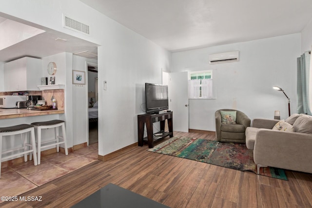 living room with visible vents, wood finished floors, and a wall mounted AC