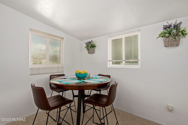 dining room featuring lofted ceiling, carpet flooring, and baseboards