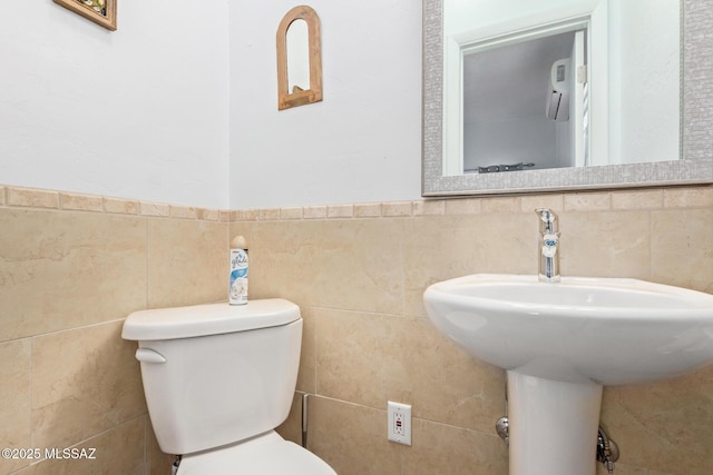 half bath with tile walls and toilet