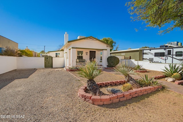 view of front of house with a gate, fence, a chimney, and stucco siding