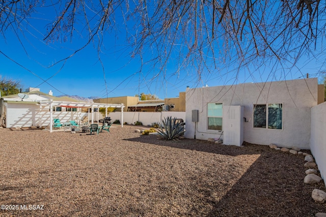 back of house featuring fence private yard, stucco siding, and a pergola