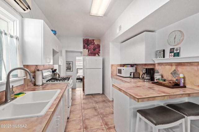 kitchen with a wall unit AC, white appliances, a sink, a wealth of natural light, and decorative backsplash