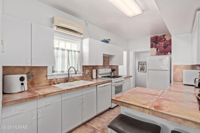 kitchen featuring white appliances, white cabinets, a sink, an AC wall unit, and backsplash