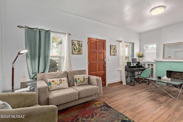 living area with a brick fireplace, baseboards, and wood finished floors