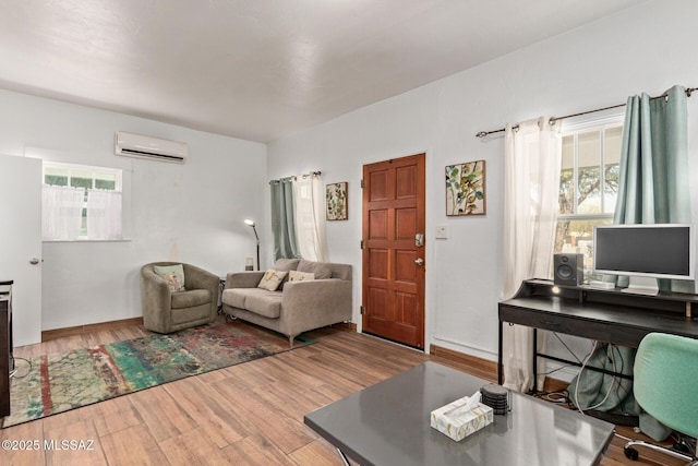 living room featuring a wall unit AC, wood finished floors, and baseboards