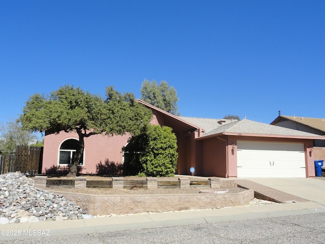 view of front facade featuring driveway, a garage, fence, and stucco siding