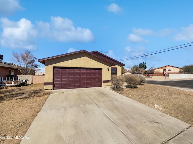 ranch-style house with concrete driveway, fence, an attached garage, and stucco siding