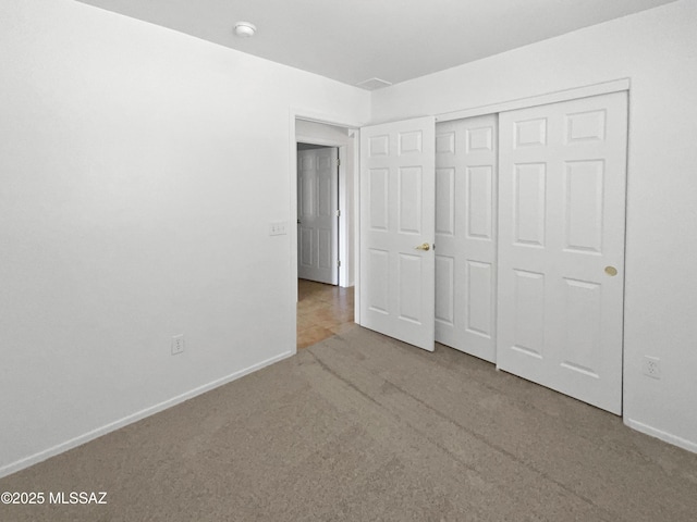 unfurnished bedroom with baseboards, a closet, and light colored carpet