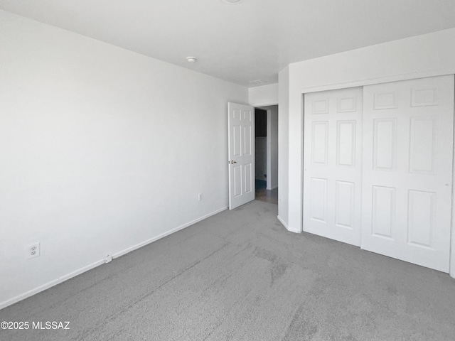 unfurnished bedroom featuring baseboards, a closet, and carpet flooring