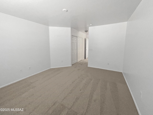 empty room featuring light carpet and baseboards