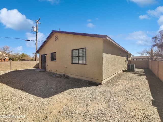 view of property exterior with a fenced backyard, central AC, and stucco siding