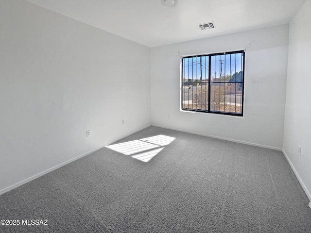 spare room with carpet floors, visible vents, and baseboards