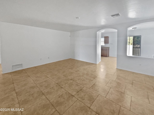 spare room with arched walkways and visible vents