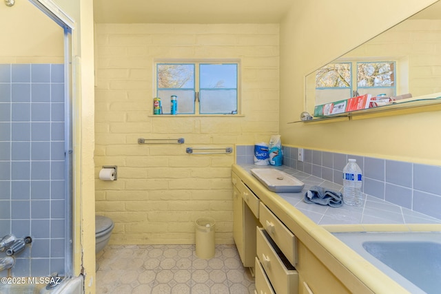 bathroom featuring vanity, toilet, and tile walls