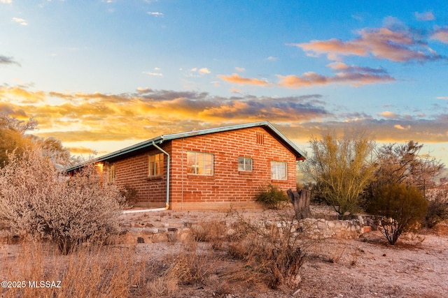 property exterior at dusk featuring brick siding