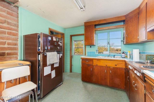 kitchen featuring light floors, brown cabinetry, light countertops, and freestanding refrigerator